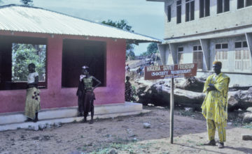 Obiekwe beside Ezumezu Childbirth shrine and his newly-presented Nigerian-Soviet Friendship Society placard, 1961